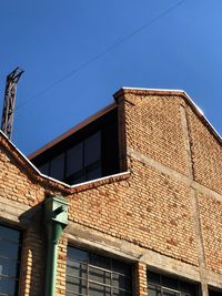 Low angle view of old brick factory building against blue sky
