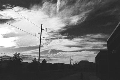 Low angle view of electricity pylon against cloudy sky