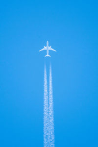 Low angle view of airplane flying against clear blue sky