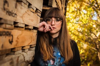 Portrait of a young woman standing against tree