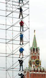 Men standing on metal built structure against spasskaya tower
