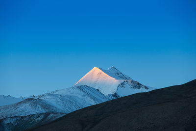 Built structure on snowcapped mountain against blue sky