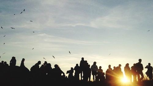 Silhouette people looking at sunset