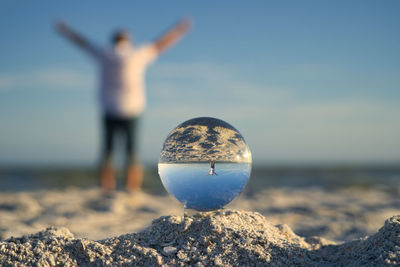 Close-up of crystal ball on rock at beach against sky