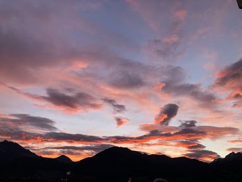 Silhouette mountains against dramatic sky during sunset