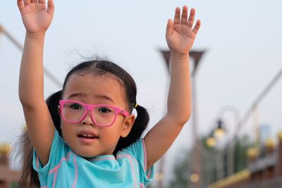 Portrait of cute girl with arms raised on footbridge