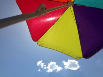 Low angle view of multi colored umbrella against blue sky