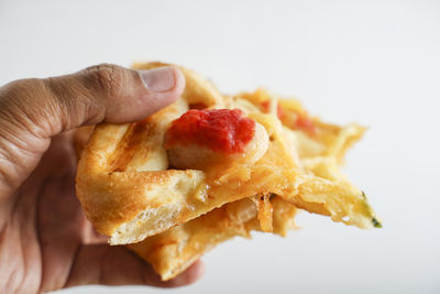 Close-up of hand holding burger against white background