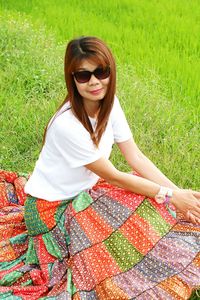 Portrait of woman in sunglasses siting on field