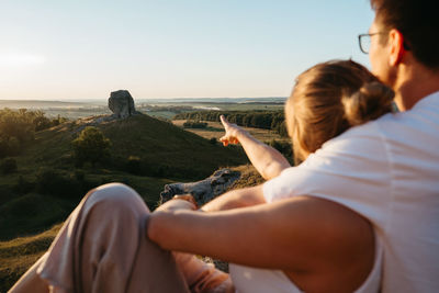 Man and woman enjoying beautiful sunset outdoors, scenic landscape and nature miracle giant stone