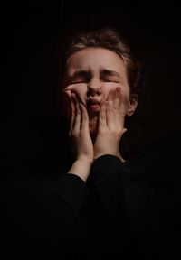 Portrait of young woman against black background
