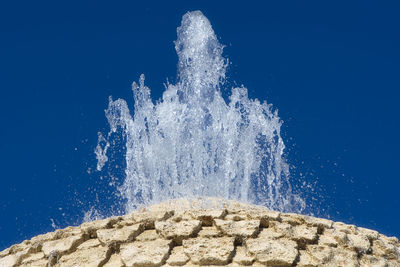 Low angle view of waterfall against clear blue sky