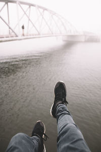 Low section of man standing on bridge against sky