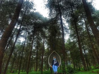 Woman standing by trees in forest