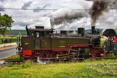 Train on railroad track against cloudy sky