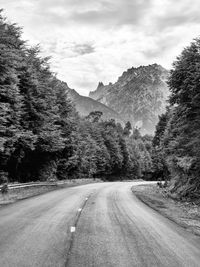 Empty road amidst trees against sky