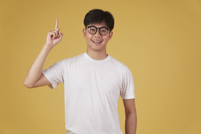 Portrait of teenage girl standing against yellow background