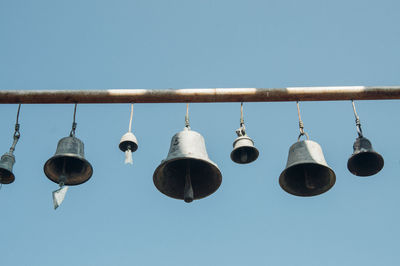 Low angle view of bells hanging against sky