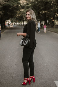 Full length portrait of woman standing against city in background