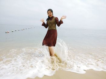 Full length of young woman standing in sea