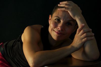 Portrait of young woman against black background