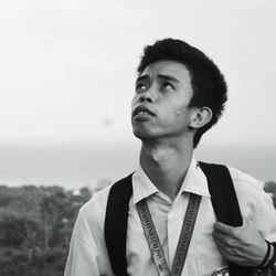 Thoughtful teenage boy looking up against sky