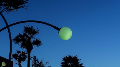 Low angle view of palm tree against clear blue sky