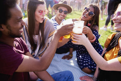 Friends toasting drinks in glasses against sky