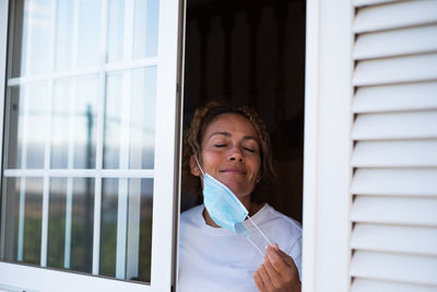 Portrait of beautiful young woman holding window