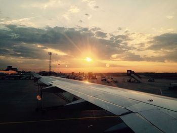 Airplane on airport runway against sky during sunset