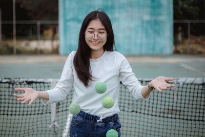 Young woman playing with balls at tennis court