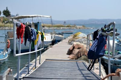 Clothes hanging on railing over pier against sea