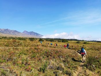 People on field by mountains against sky