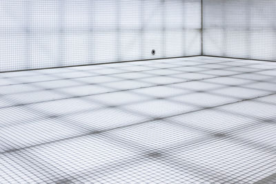 A sterile white room of unknown function with grid-like walls and floors