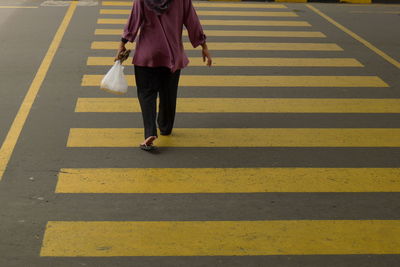 Low section of woman walking on zebra crossing