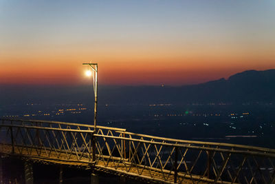 Illuminated bridge against sky at sunset