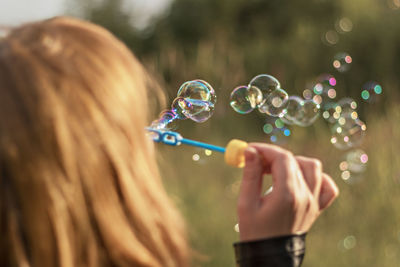 Rear view of woman blowing bubbles