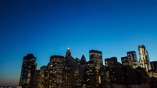 Low angle view of illuminated buildings against blue sky