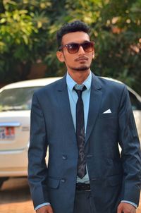 Handsome businessman wearing suit while standing against car