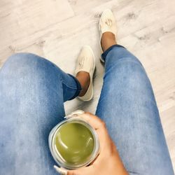 Low section of woman holding drink while sitting at home