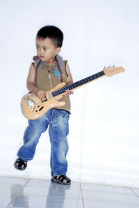 Boy playing guitar against wall
