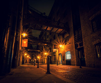 Illuminated street amidst buildings at night