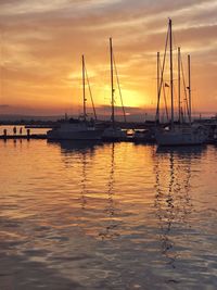 Sailboats in sea at sunset