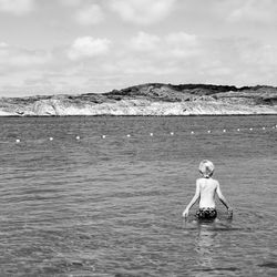 Woman standing in sea against sky