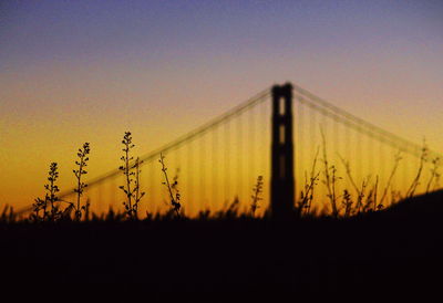 Silhouette of suspension bridge against clear sky during sunset