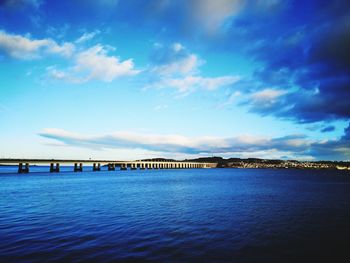 Bridge over sea against blue sky