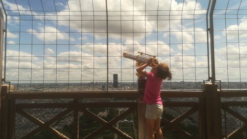 Full length of woman photographing railing against sky