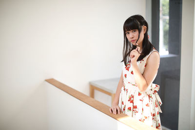 Woman standing against wall at home