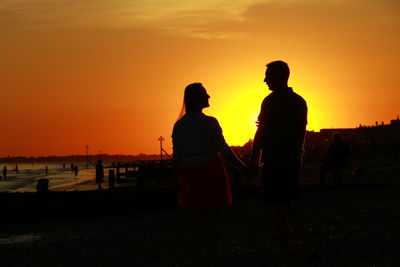 Silhouette people on beach during sunset