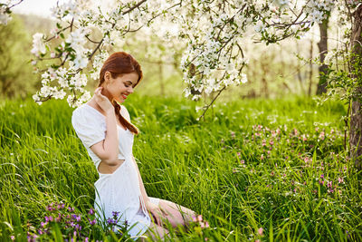 Side view of young woman sitting on field